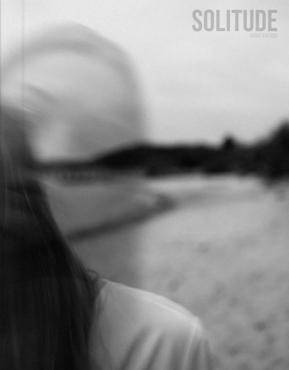 Okładka albumu „Solitude.”: czarno-białe, rozmyte ujęcie postaci na pustej plaży.